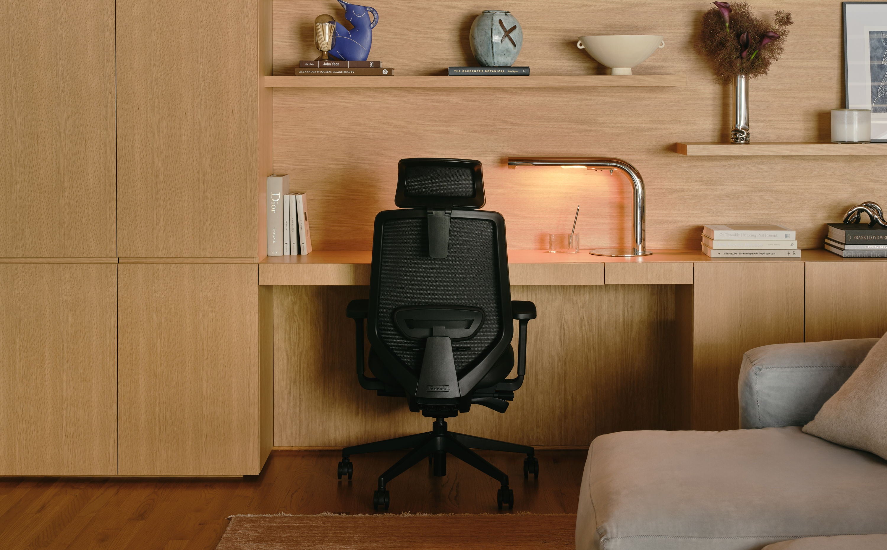 A modern workspace with a black chair and wooden shelving.