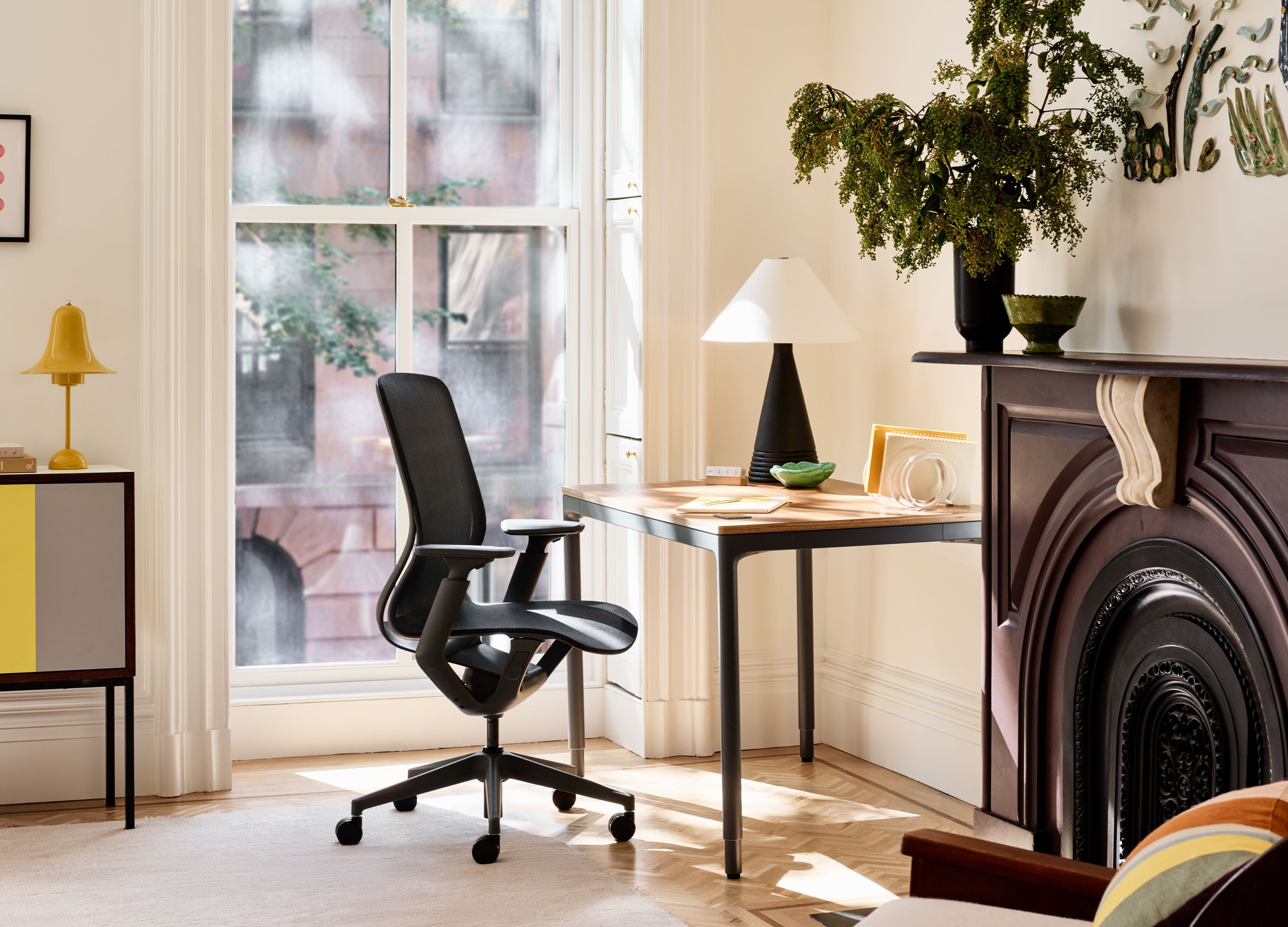 A modern workspace featuring a chair, desk, lamp, and decorative plants.